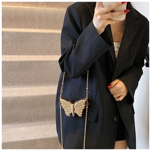 Vue détaillée du mini sac papillon en métal doré porté sur un blazer noir chic