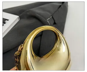 Detail of gold moon handle and mirror-finish metallic surface on luxury acrylic clutch bag