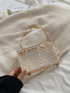Detail of transparent acrylic box bag with golden metal frame and V-shaped stripes