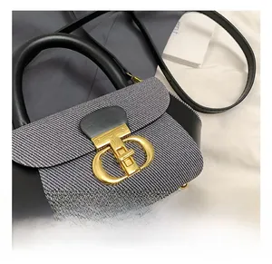 Detail of grey woven fabric bag featuring a signature golden metal twist lock closure