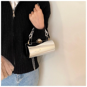 Detail of silver mirror cylinder bag featuring pearl clasp and dual chain straps
