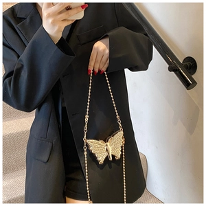 Vue détaillée d'une pochette papillon dorée avec strass brillants et bandoulière en chaîne