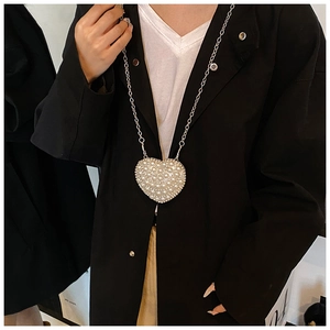 Detail of a heart-shaped mini bag with white pearls, rhinestones, and silver chain strap