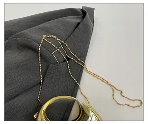 Detailed close-up of the elegant gold beaded chain strap and polished metal handbag handle