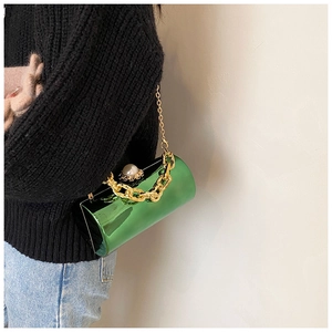 Detail of emerald green cylinder evening bag with gold chain and pearl clasp