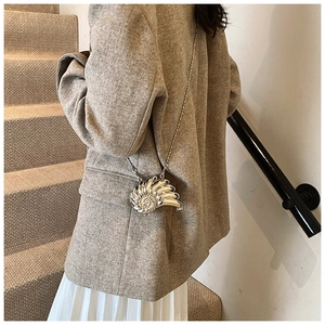 Mini borsa a tracolla argentata a forma di conchiglia indossata su un blazer moda