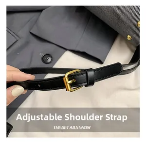 Macro detail of adjustable black lychee leather shoulder strap with gold metal buckle