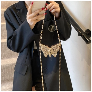Détail d'un mini sac papillon en métal doré avec texture perlée et strass scintillants