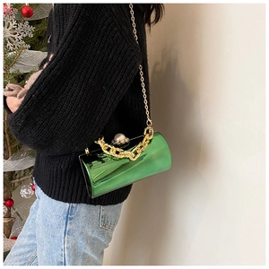 Detail of emerald green cylinder evening bag with gold chain and large pearl clasp