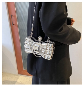 Detail of silver bow-shaped evening clutch with grid texture and pearl chain strap