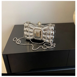 Detail of silver bow clutch with pearl closure and detachable beaded chain strap