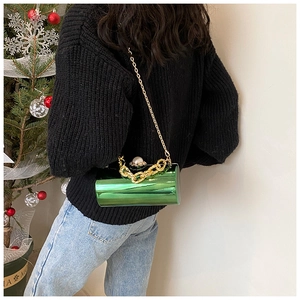 Detail of green patent leather bucket bag with pearl clasp and gold chain straps