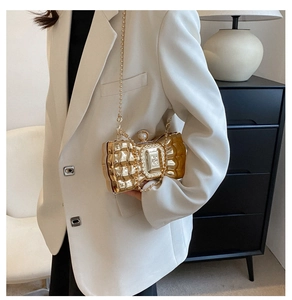 Detail of golden bow-shaped evening clutch with quilted metal finish and pearl clasp