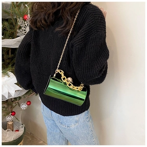 Detail of green acrylic cylinder bag with gold chain and pearl on holiday outfit