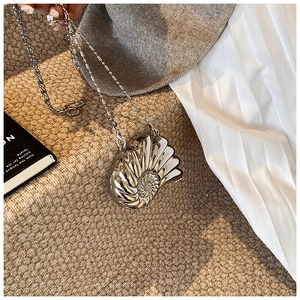 Dettaglio pochette a conchiglia argento con texture a spirale e tracolla a catena