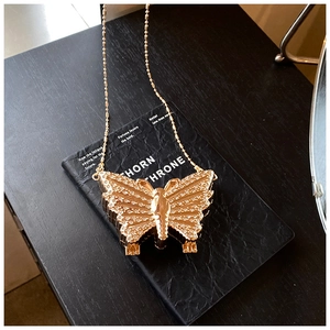 Détail du sac papillon doré orné de strass posé sur la surface d'un livre noir