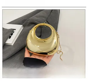 Detailed close-up of golden metallic mini handbag with round handle and bead chain
