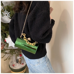 Detail of green patent leather bucket bag featuring pearl clasp and gold chain straps