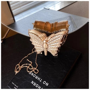 Détail d'un sac de soirée papillon doré orné de strass brillants et d'une chaîne