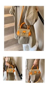 Detail of a khaki woven crossbody bag with orange leather accents and a gold buckle