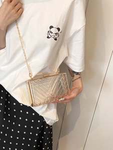 Close-up of clear acrylic box bag with gold metal frame and V-shaped geometric textures