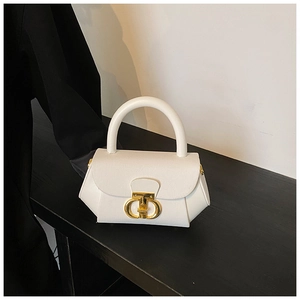 Detail of white leather handbag with gold CD metal buckle on a black textured surface
