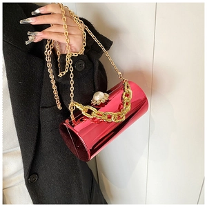 Close-up of red mirror cylinder bag with gold chain strap and pearl buckle