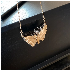 Gros plan d'un pendentif papillon 3D avec strass sur une chaîne à billes dorée