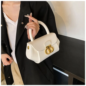 Close-up of white pebble leather bag featuring a prominent gold interlocking metal buckle