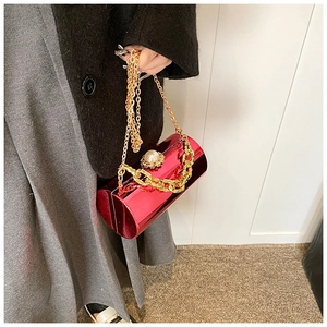 Detailed shot of red cylindrical evening bag with gold chain and large pearl clasp