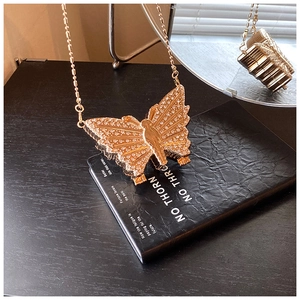 Vue détaillée du mini sac papillon doré orné de strass brillants avec sa fine chaîne dorée