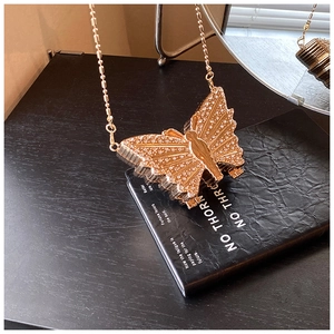 Détail macro du mini sac papillon doré avec strass scintillants et chaîne à billes