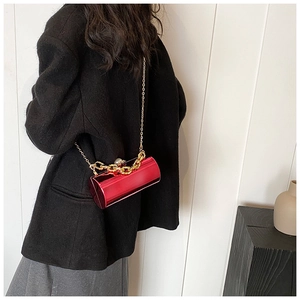 Detail of red acrylic cylindrical bag with pearl clasp and gold chain on model