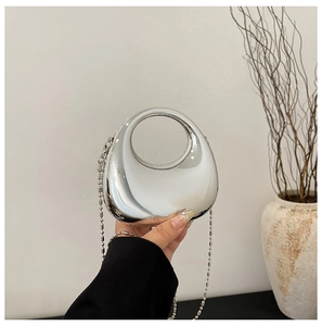 Detail of silver metallic crescent bag with round handle and elegant beaded chain strap