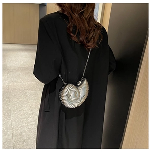 Silver snail-shaped metallic party clutch bag on a model wearing a black coat
