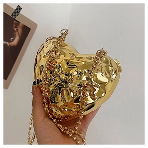 Dettaglio mini borsa a cuore dorata metallizzata con trama fluida e catena a palline