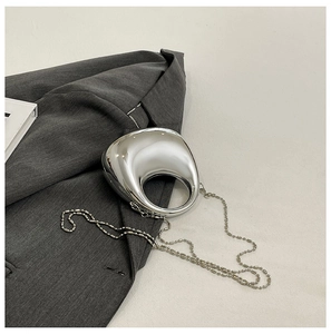 Detail of silver mirror crescent bag with metallic bead chain on gray suit jacket