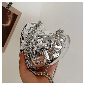Dettaglio borsa a cuore in metallo argento con trama liquida e catena a perline
