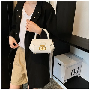 Detail of white structured handbag with elegant gold T-clasp and pebbled leather texture