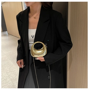 Chic gold mirrored acrylic clutch bag with round handle shown as a stylish crossbody detail