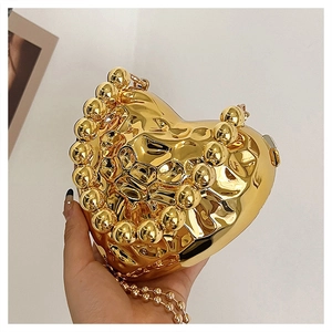 Dettaglio ravvicinato di una borsa da sera dorata a cuore con trama in metallo fluido