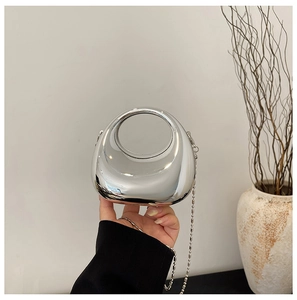 Detail view of a metallic silver evening bag with a round handle and beaded chain strap
