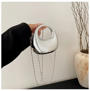 Macro shot of silver acrylic moon handbag with metallic mirror finish and bead chain