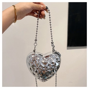 Dettaglio borsa a cuore in metallo argento con trama martellata e catena a sfere