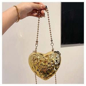 Dettaglio della borsa da sera a cuore con trama martellata e catena a sfere dorate