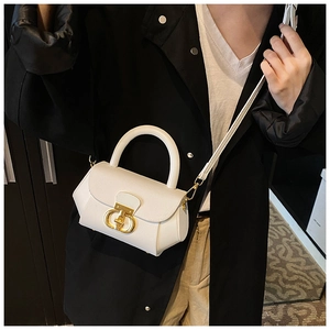 Detail of white textured leather handbag featuring a vintage gold metal twist lock