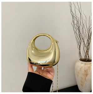 Detail of minimalist gold crescent acrylic evening bag with metallic mirror finish and chain