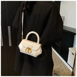 Detail of cream white leather shoulder bag with gold metal buckle and round handle