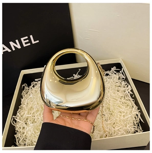 Detail of gold acrylic half-moon evening bag with integrated handle and chain strap