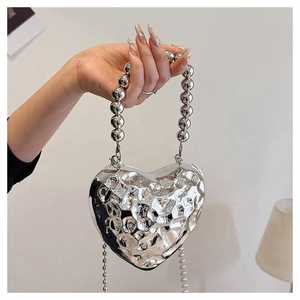 Dettaglio della borsa a cuore argento con trama metallica martellata e manico di perle